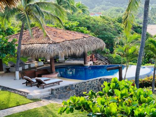 a resort with a swimming pool and a hut at Casa Manzanillo - Sunset Room - Ocean Front Room at Exceptional Beach Front Location in Troncones