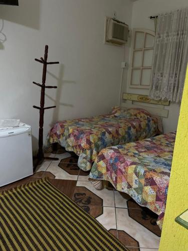 a room with two beds and a cross on the floor at Pousada Oca Porã in Conservatória