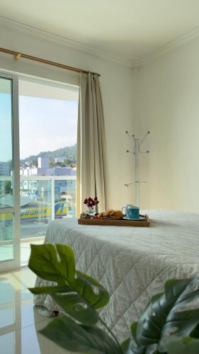 a bedroom with a bed with a cross in the window at Apto Lírio da Paz- 3 Quartos com sacadas,espaçoso e de frente para avenida principal! in Piratuba