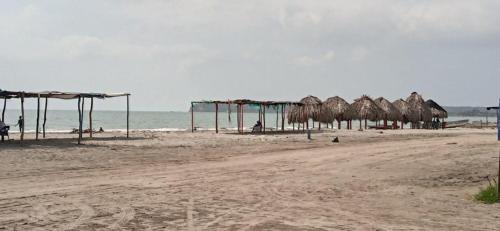 a beach with a bunch of straw umbrellas and the ocean at HOSTAL LA BOQUILLA in Cartagena de Indias