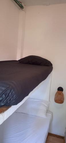 a bed with a black pillow on a white wall at HOSTAL LA BOQUILLA in Cartagena de Indias