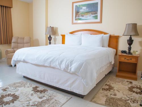 a bedroom with a large white bed and a chair at Princess Vegas Hotel & Casino in Corozal