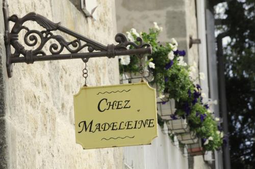 a sign hanging on a building with flowers at Chez Madeleine in Saint-Colomb-de-Lauzun