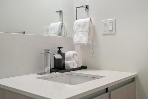 a bathroom with a sink and a mirror and towels at "The Draper" - Luxury Corner Unit w Tower View, - Near Stampede, Saddledome, BMO Centre! FREE Parking, Banff Pass, & Wine! in Calgary