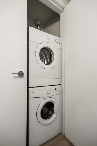 a washer and dryer in a small room at "The Draper" - Luxury Corner Unit w Tower View, - Near Stampede, Saddledome, BMO Centre! FREE Parking, Banff Pass, & Wine! in Calgary