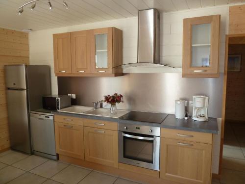 a kitchen with wooden cabinets and stainless steel appliances at Stone House in Cleder near Les Amiets Beach in Cléder