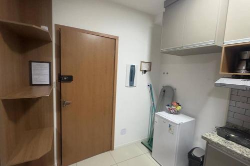 een keuken met een houten deur en een koelkast bij Lindo e aconchegante Stúdio mobiliado - Centro in Araraquara