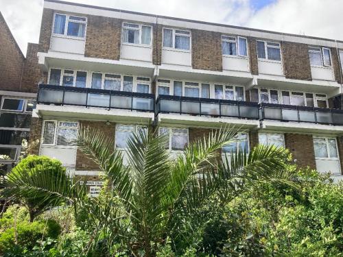 an apartment building with a palm tree in front of it at Laret Guest House in London