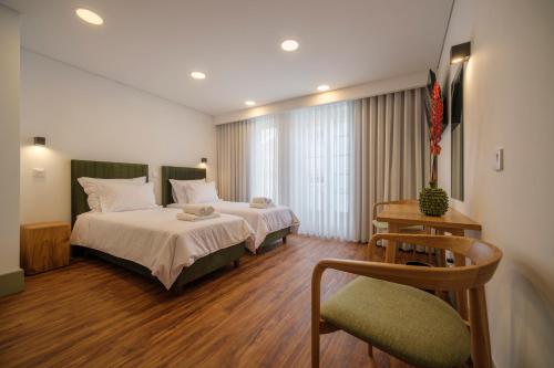 a hotel room with two beds and a chair at Azimute 4 - T0 Moderno Centro Histórico Angra in Angra do Heroísmo