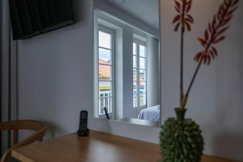a dining room with a table and a vase with a plant at Azimute 4 - T0 Moderno Centro Histórico Angra in Angra do Heroísmo
