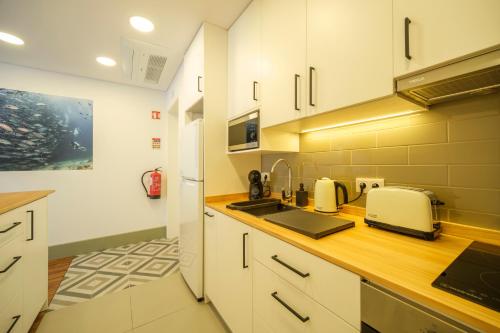 a kitchen with white cabinets and a counter top at Azimute 4 - T0 Moderno Centro Histórico Angra in Angra do Heroísmo
