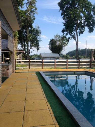 a swimming pool in front of a house at Rajawali Riverside Retreat in Dungun