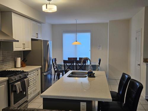 a kitchen with a sink and a table with chairs at Beautiful New Townhouse in Quiet Neighbourhood in Ajax