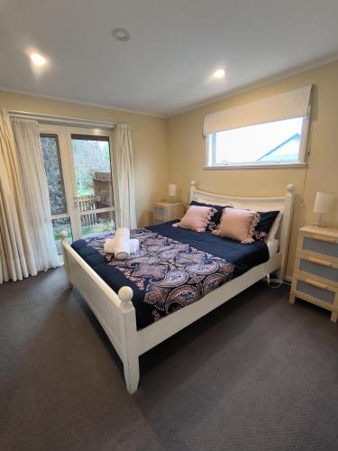 a bedroom with a bed with pink pillows and a window at Vibrant Living Retreat in Hanmer Springs
