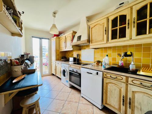 - une cuisine avec des placards en bois et un lave-vaisselle blanc dans l'établissement 3 Pieces ARENAS NICE OUEST, à Nice