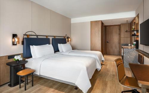 a bedroom with a large white bed and a desk at JEN Kunming by Shangri-La in Kunming