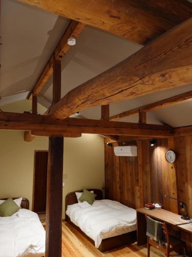two beds in a room with wooden ceilings at ゲストハウス長閑 in Toyooka