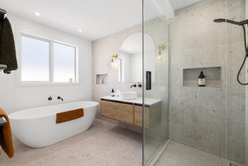 a bathroom with a tub and a sink and a shower at Seas the Day Comfort and Spa in Mount Maunganui