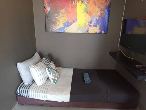 a bed with pillows and a tv in a room at Rajawali Riverside Retreat in Dungun