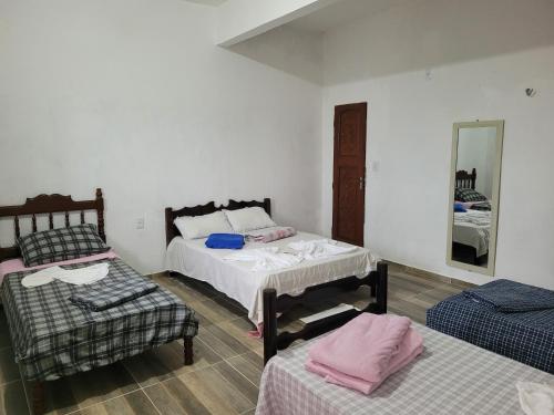 a room with two beds and a chair and a mirror at Pousada Suítes continental in Salinópolis