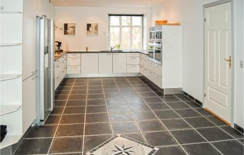 a kitchen with white cabinets and a tiled floor at Seven-Bedroom Holiday Home In Bredebro in Bredebro