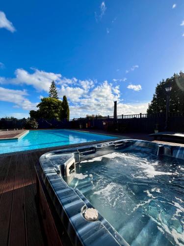 a large swimming pool with a hot tub at Tudor Manor Bed & Breakfast in Paraparaumu Beach