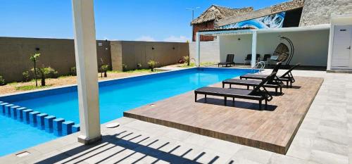 a swimming pool with two chairs and a house at Departamento Frente al Mar entre Veracruz y Boca del Rio in Veracruz