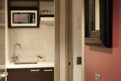 a kitchen with a sink and a microwave at Residence Mercure Paris La Defense Grande Arche in Nanterre