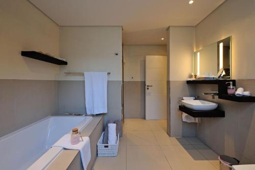 a bathroom with a tub and a sink and a toilet at 129 on Kloof Nek Apartments in Cape Town