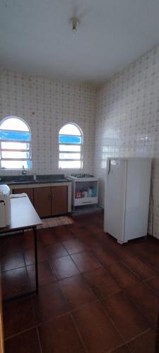 a kitchen with a white refrigerator and two windows at Sobrado para ate 8 pessoas in Barra do Garças