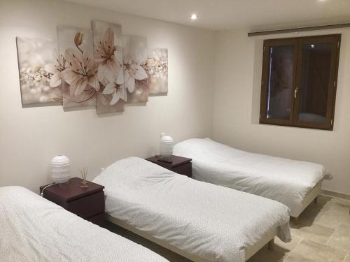 deux lits dans une chambre avec des draps blancs et des fleurs au mur dans l'établissement Gîte G3173, à Vidauban