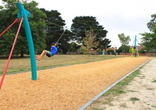 a young boy is swinging on a playground at Modern Townhouse - Cafes, Shops, Bus, Freeway access in Balwyn North
