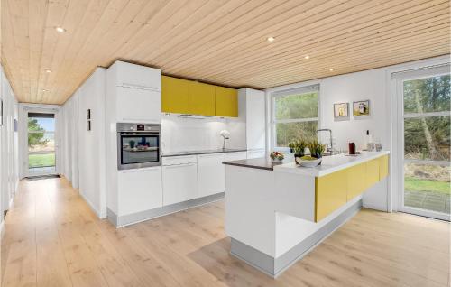 a kitchen with white cabinets and a wooden ceiling at Holiday Home Rømø With Fireplace 06 in Rømø