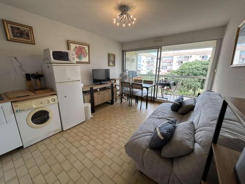 un salon avec un canapé et une cuisine avec une table dans l'établissement Studio Cabine 4 couchages, proche Seaquarium, plage et commerces, avec terrasse et barbecue, Le Grau-du-Roi - FR-1-250-289, au Grau-du-Roi