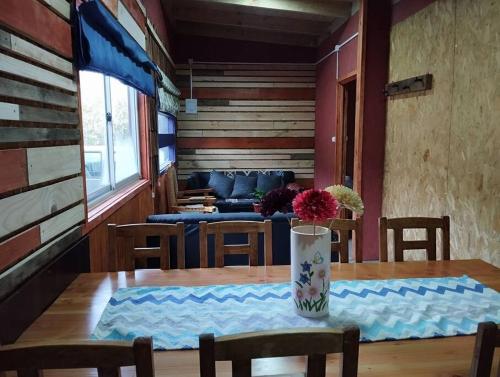 a dining room with a table with chairs and a couch at Cabaña Choroy dentro del pueblo, cercano a playas in Licán Ray