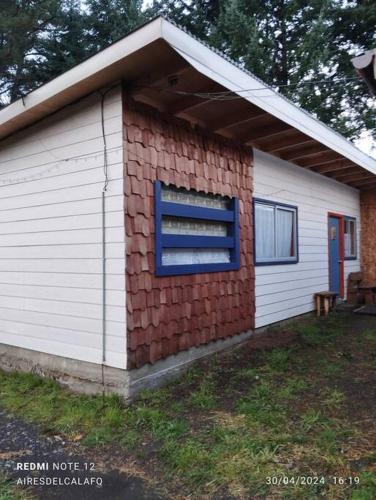 a garage with a brick wall and a blue window at Cabaña Choroy dentro del pueblo, cercano a playas in Licán Ray