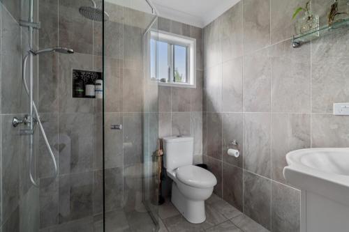 a bathroom with a toilet and a shower and a sink at Driftwood Callala Plus - Jervis Bay Getaway - 10 Guests! in Callala Bay