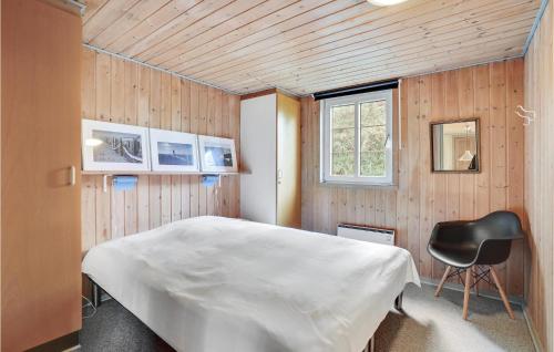 a bedroom with a white bed and a black chair at Holiday Home Dyssebjergvej Rømø Ii in Rømø Kirkeby