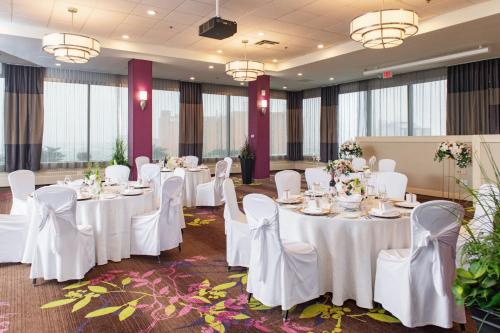 a banquet hall with white tables and chairs and windows at Holiday Inn Toronto International Airport by IHG in Toronto