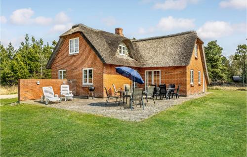 a house with a table and chairs and an umbrella at Four-Bedroom Holiday Home In Romo in Rømø