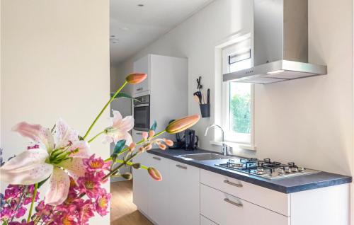 a kitchen with white cabinets and a sink and flowers at 3 Bedroom Cozy Home In Heinkenszand in Heinkensand