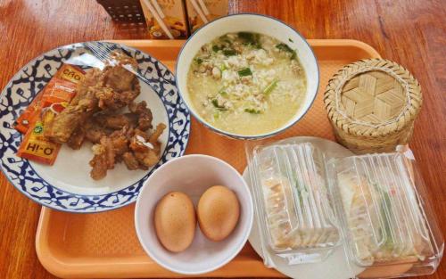 een dienblad met eten, schalen met eten en een kom soep bij Arawan Resort เอราวัณ รีสอร์ท in Ngao