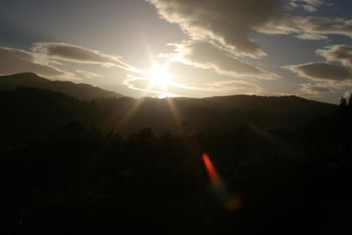 a sunset with the sun shining over the mountains at BCC Loch Ness Hostel in Bearnock