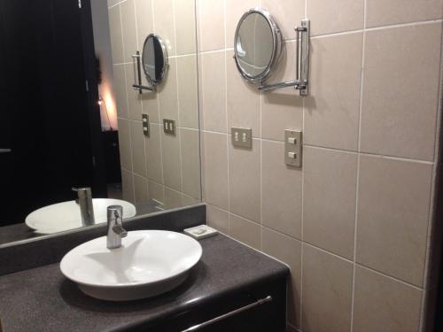 baño con lavabo y 2 espejos en la pared en Hotel Brandts Ejecutivo Los Robles, en Managua