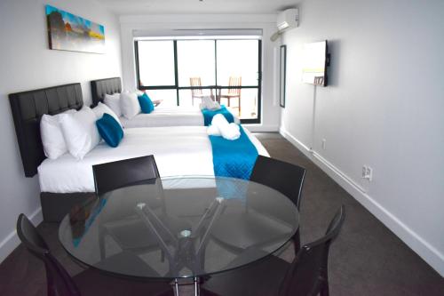 a bedroom with a glass table in front of a bed at 6 on Adams in Mount Maunganui