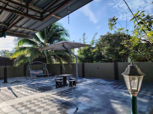 a patio with a table and an umbrella at The Garden Homestay Kemaman in Kemaman