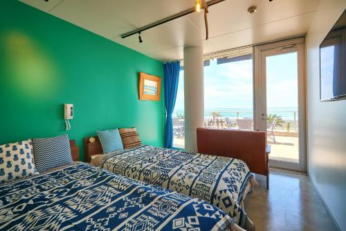 two beds in a room with a green wall at zaimokuza seasons in Kamakura