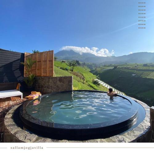 a person in a swimming pool with mountains in the background at Villa The Noman Tawangmangu by Suasana Villa in Sarangan