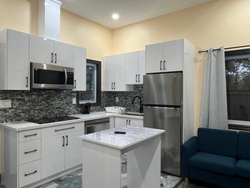 a kitchen with white cabinets and a stainless steel refrigerator at The Grassy Oasis in Brampton