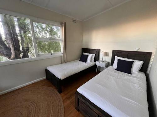 ein Schlafzimmer mit zwei Betten und einem Fenster in der Unterkunft Pine Hill Cottage - shabby chic & peaceful haven in Katoomba